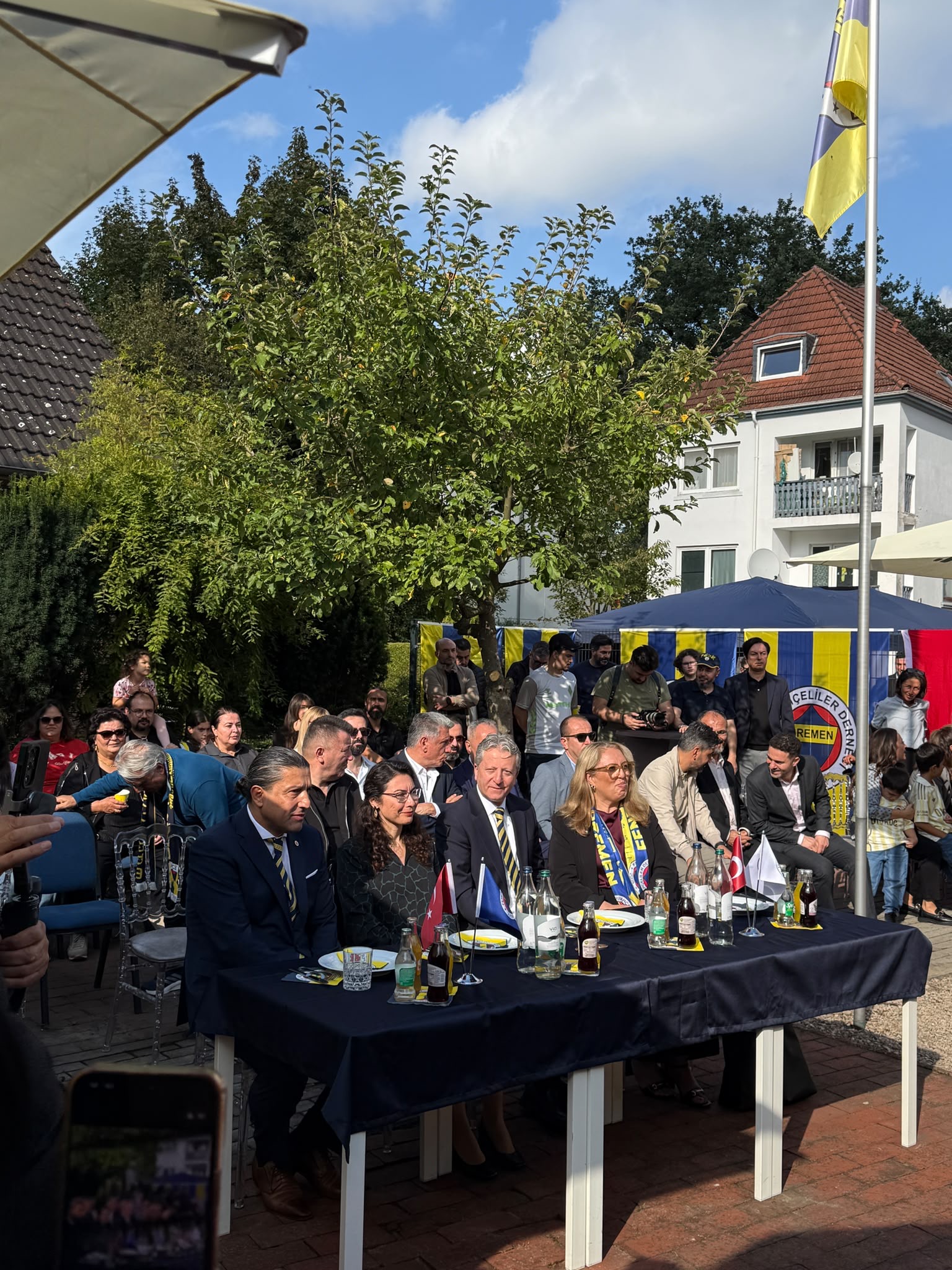 Gäste sitzen während der Eröffnungsfeier des Bremen Fenerbahçeliler Derneği im Außenbereich.
